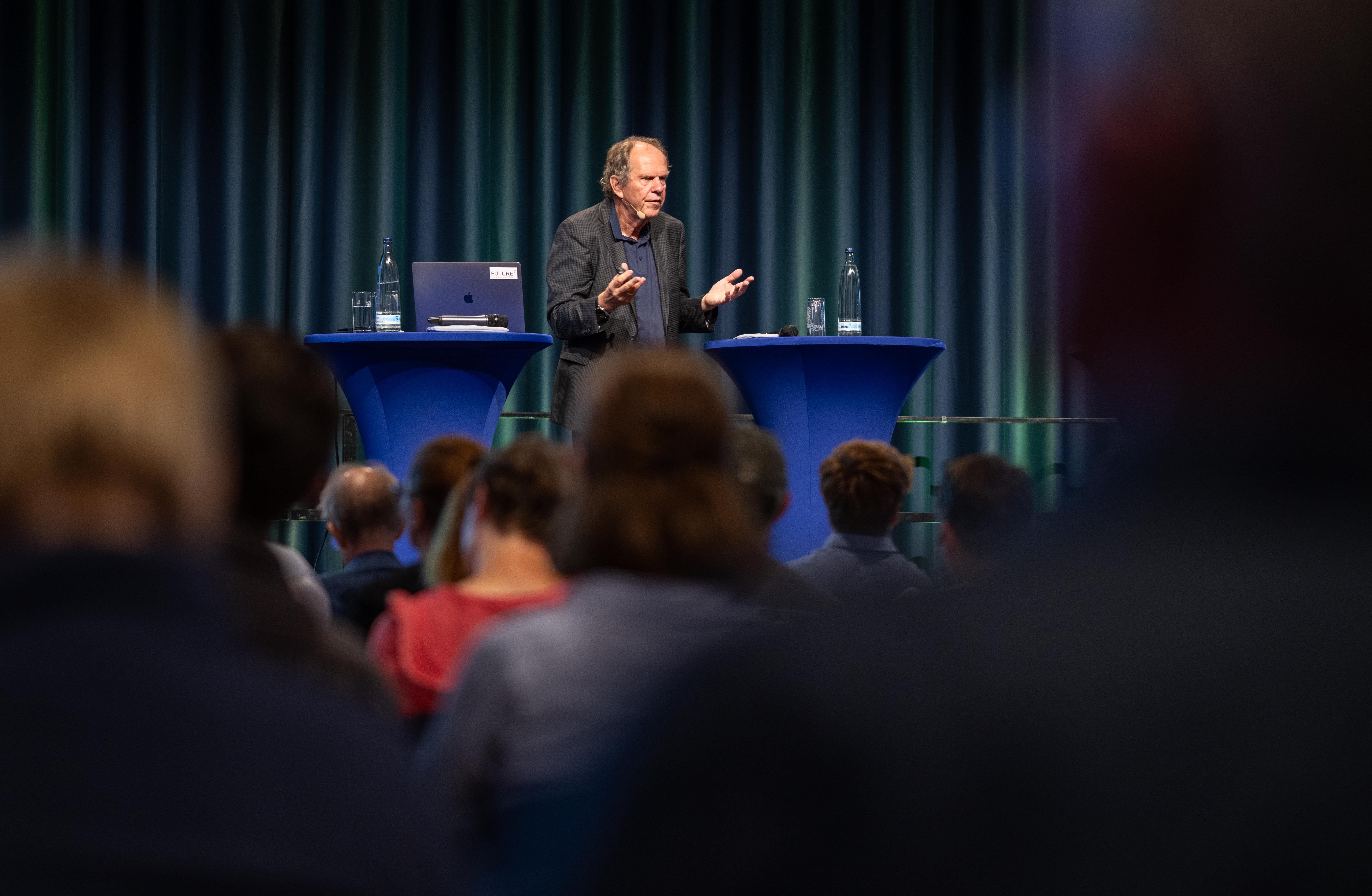 Prof. Burow hält auf einer Bühne einen Vortrag.