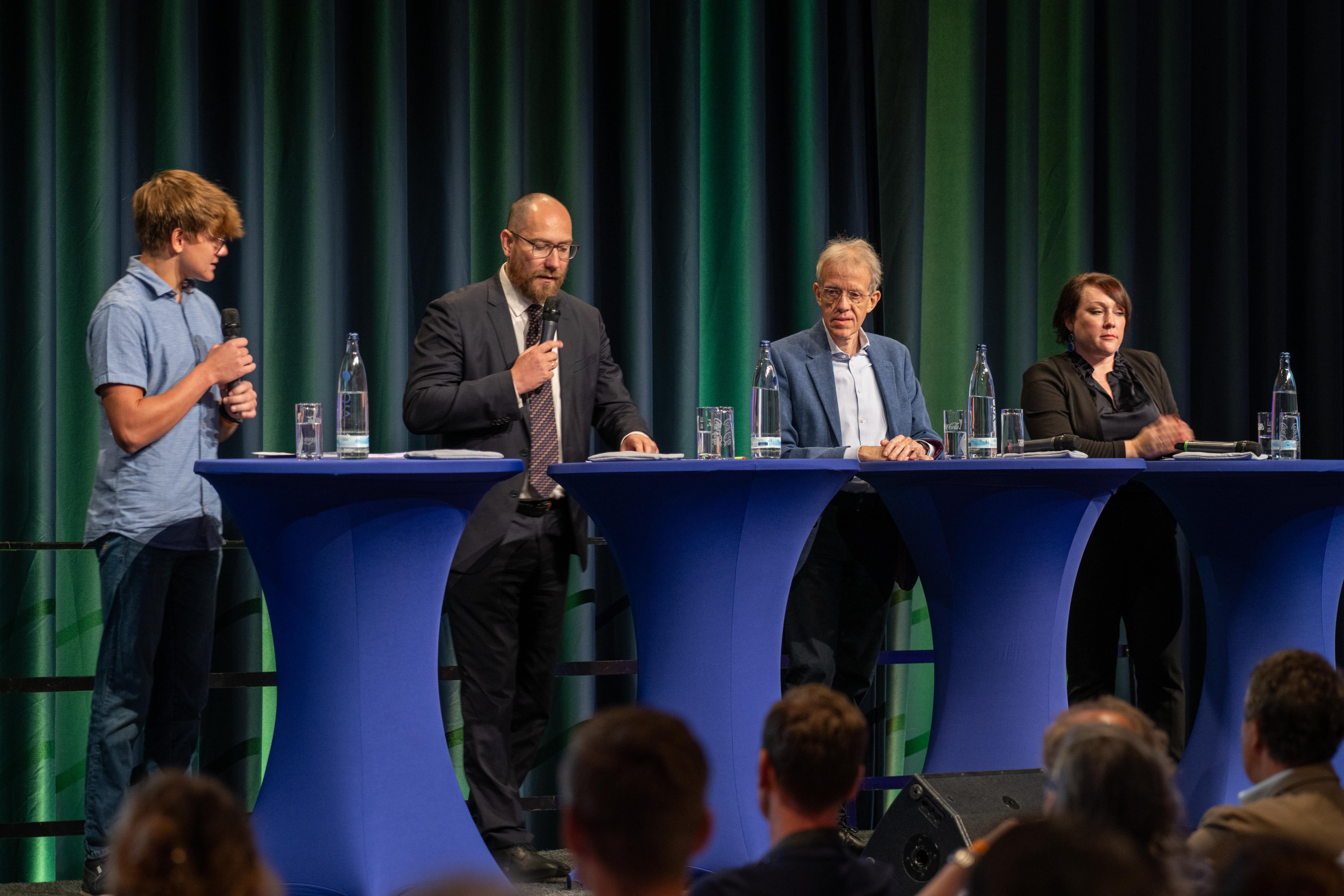 Drei Männer und eine Frau führen ein Podiumsgespräch.