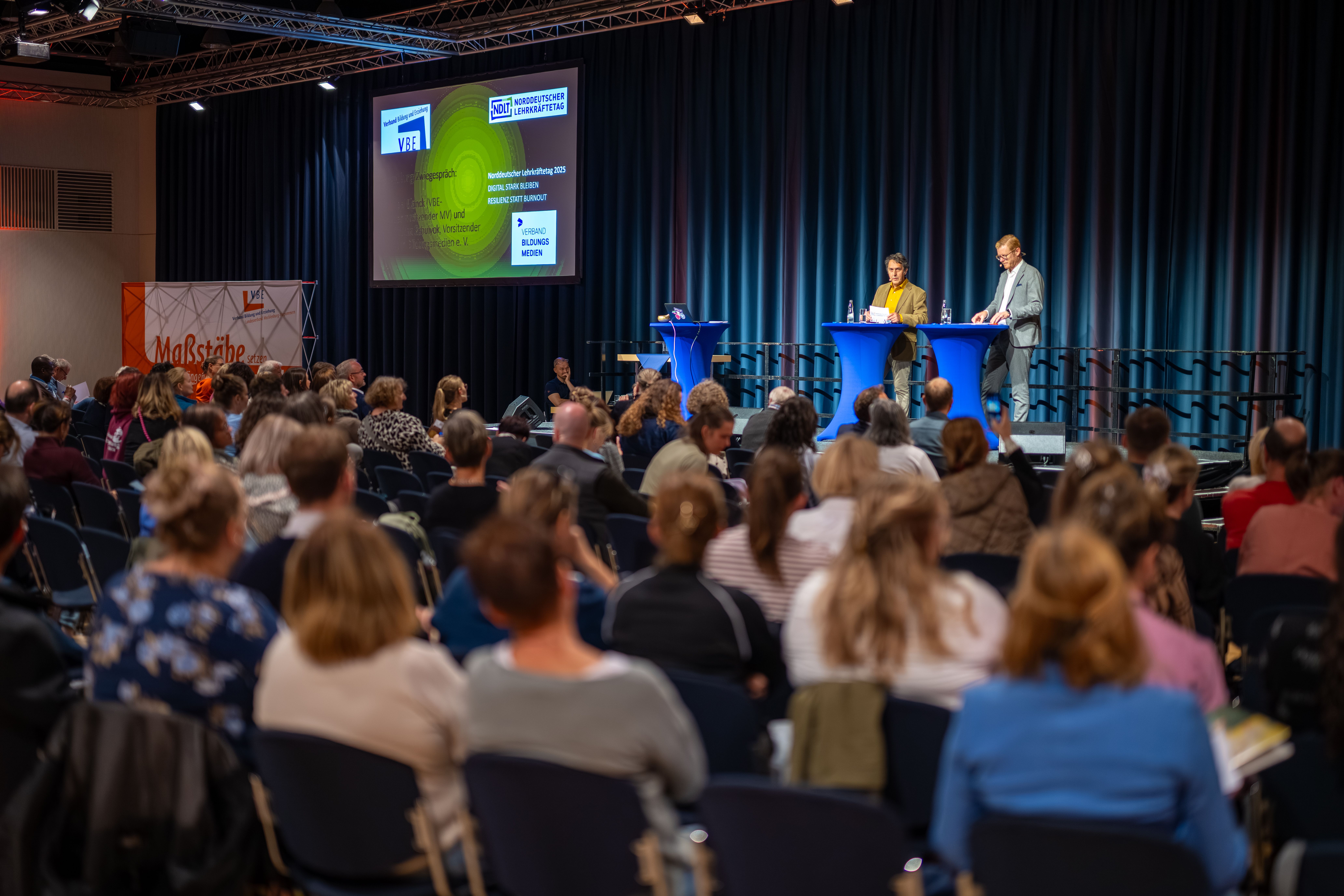 Michael Blanck und Maximilian Schulyok stehen auf einer Bühne und sprechen miteinander