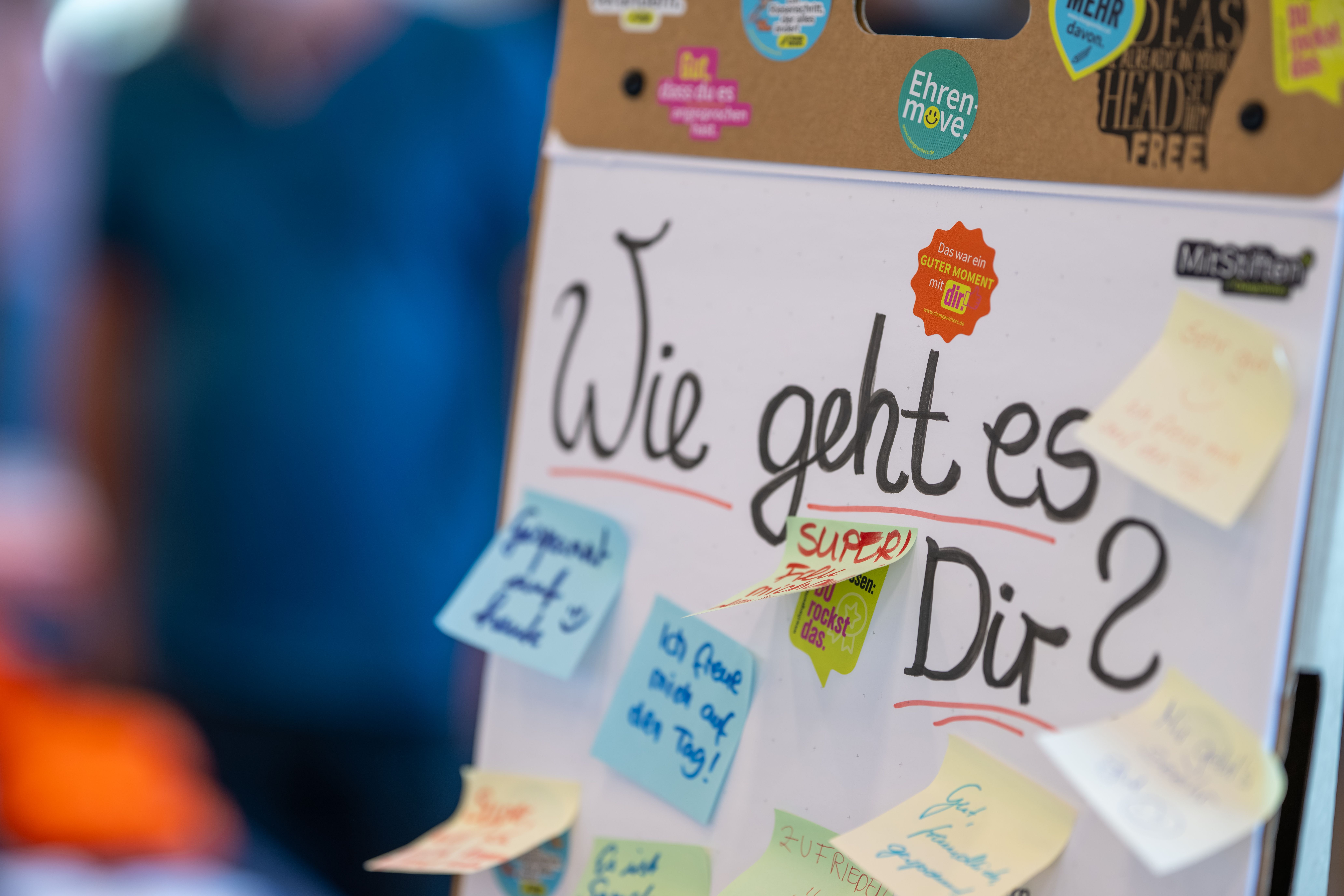 Auf einer Pinwand hängt ein Zettel mit der Frage "Wie geht es dir?"