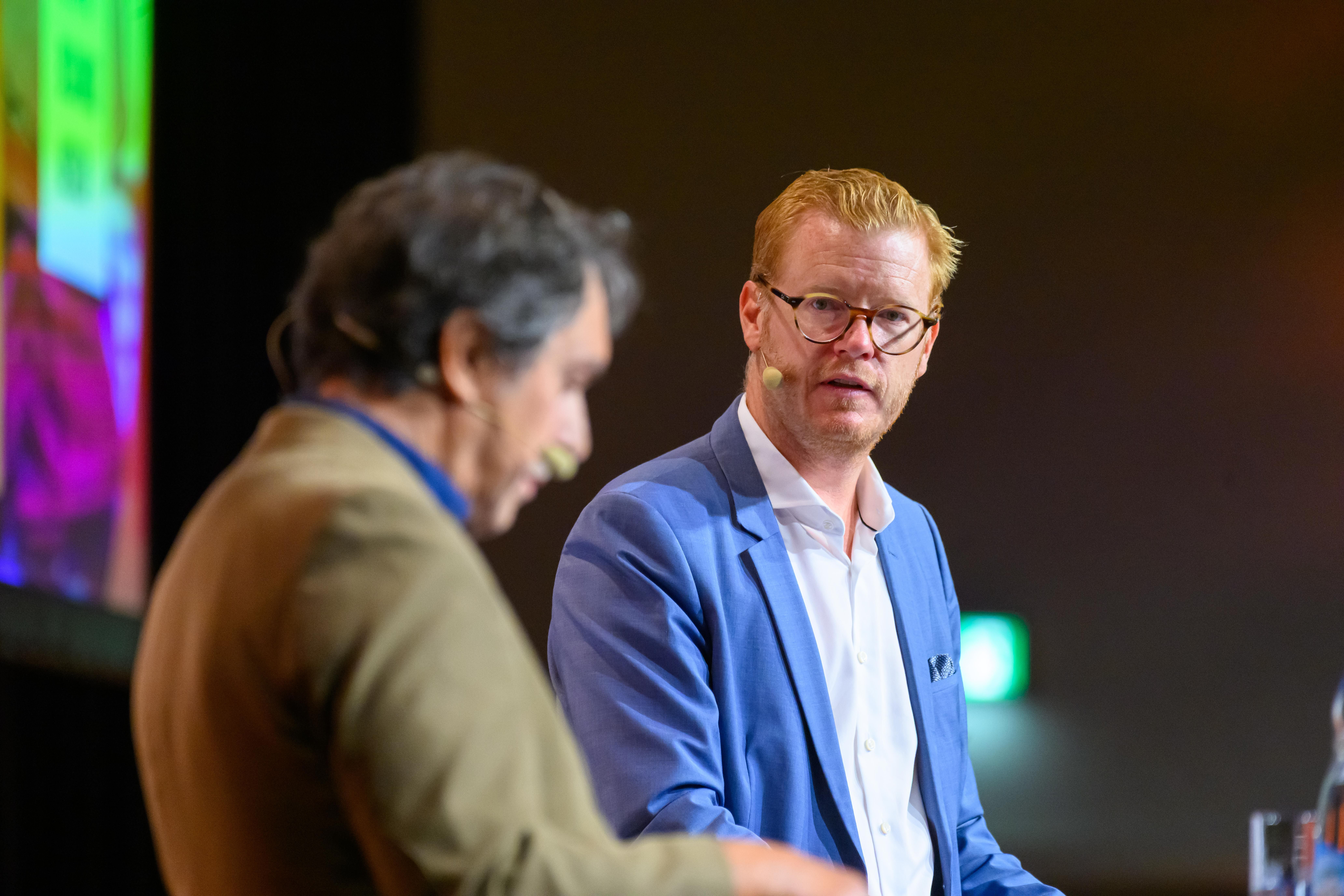 Maximilian Schulyok spricht auf einer Bühne mit Michael Blanck.