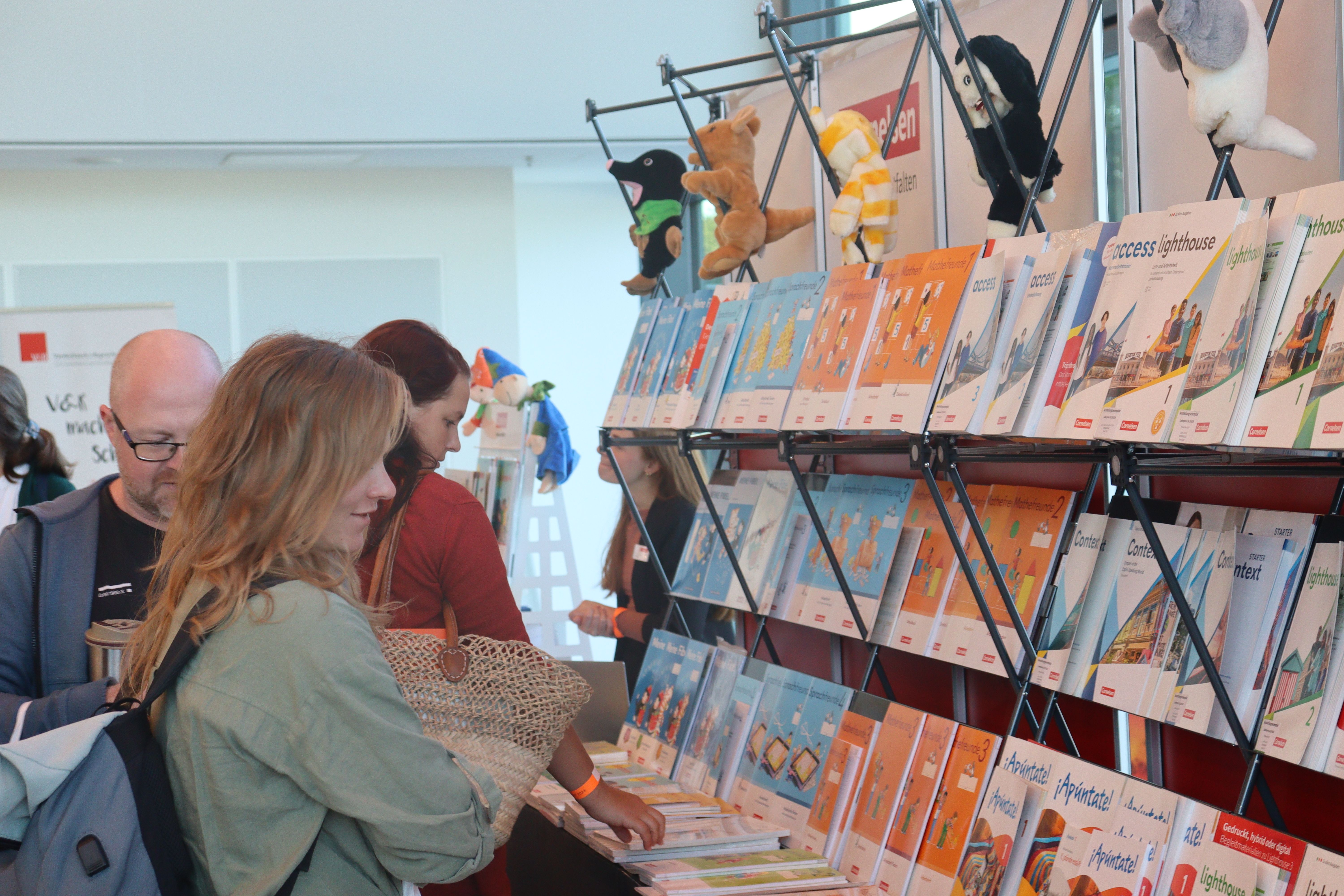 Lehrkräfte schauen an einem mobilen Messestand Schulbücher an.