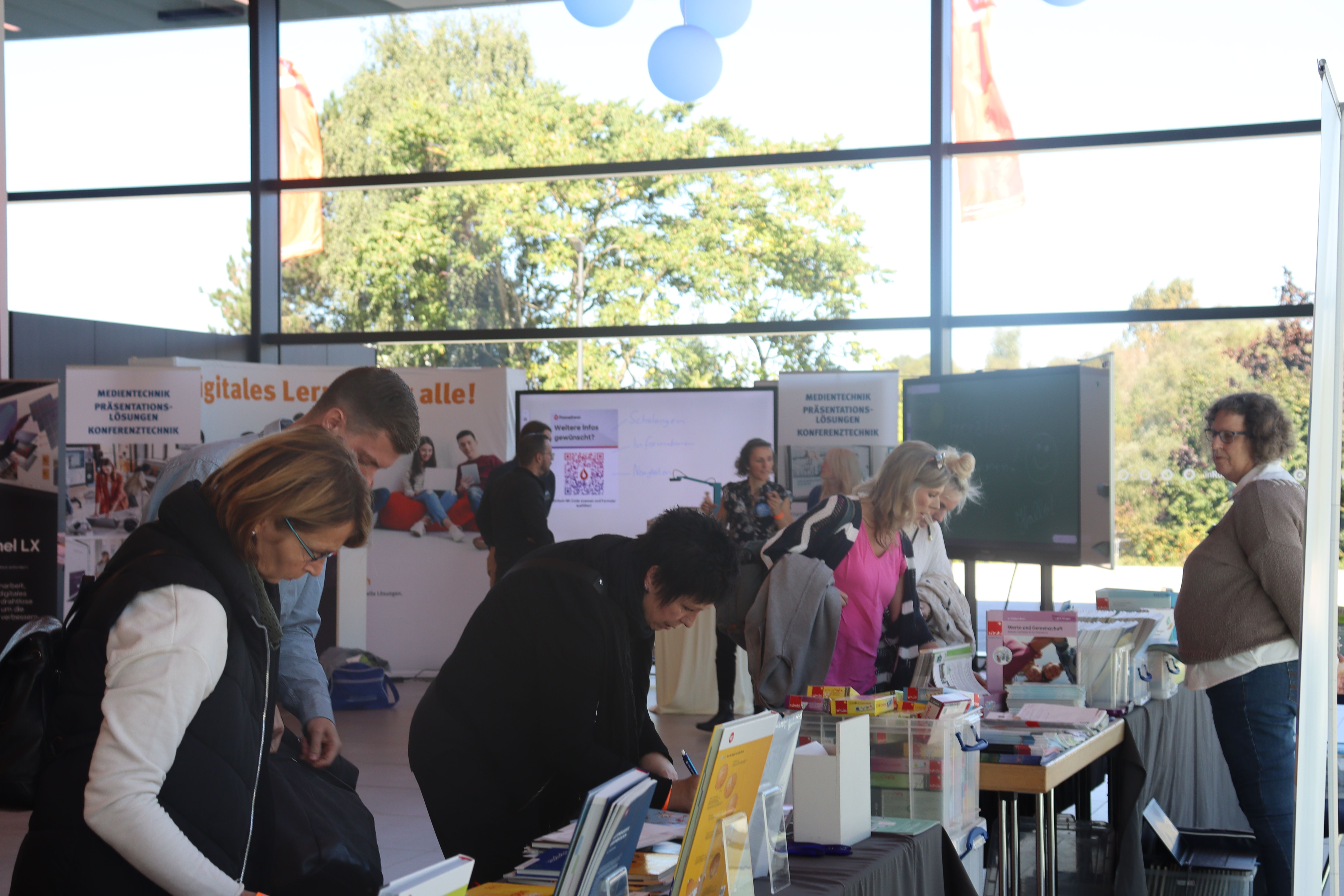 Lehrkräfte schauen an einem mobilen Messestand Bücher an.